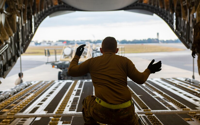 A photo of an Airman guiding cargo onto a C-17.