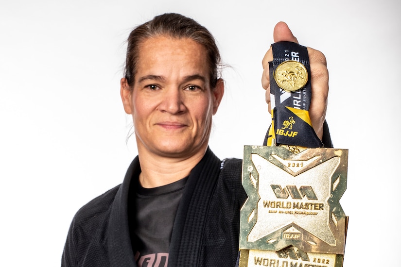 An airman in a black martial arts robe holds up a medal.