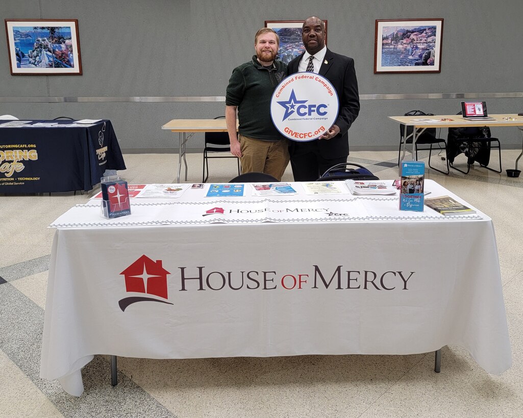 two people behind a table holding cfc logo