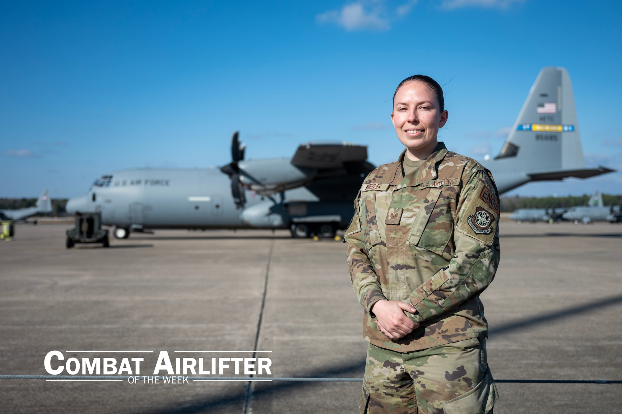 A woman in uniform poses for a photo in front of an aircraft