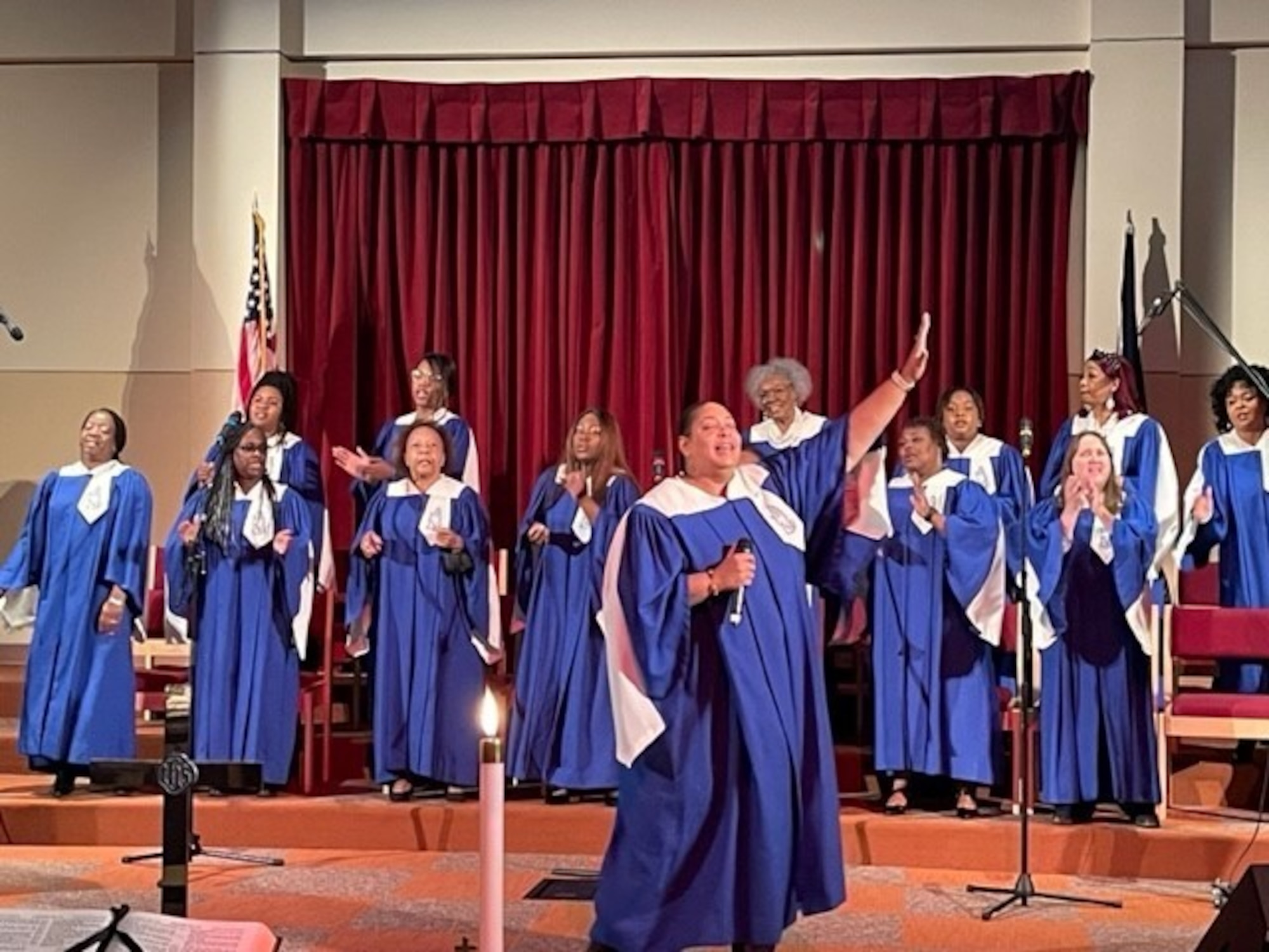 A gospel choir donned in blue and white robes perform in a chapel.