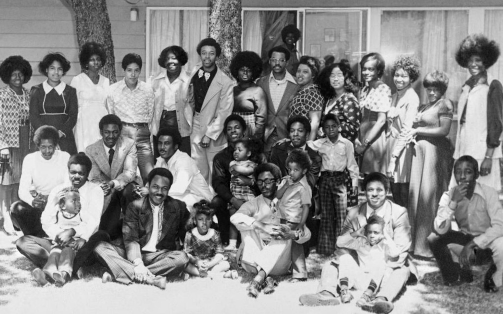 A black-and-white of more than 30 people posing for a group in a backyard in 1974.