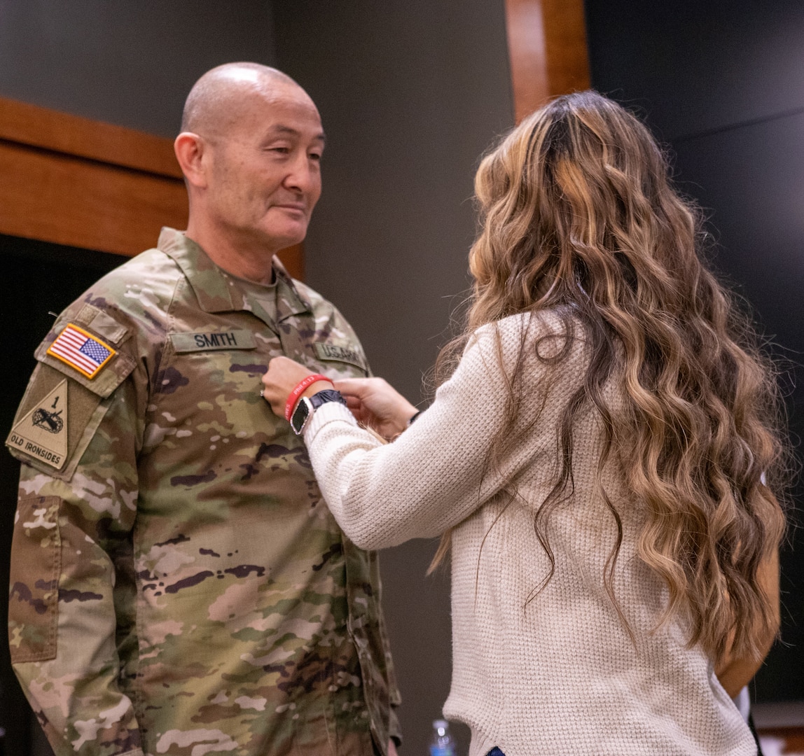 Reegan Smith, daughter of newly promoted Col. Eric Smith, of Springfield, affixes the colonel rank on his uniform during a promotion ceremony Jan. 13 at Camp Lincoln, Springfield.