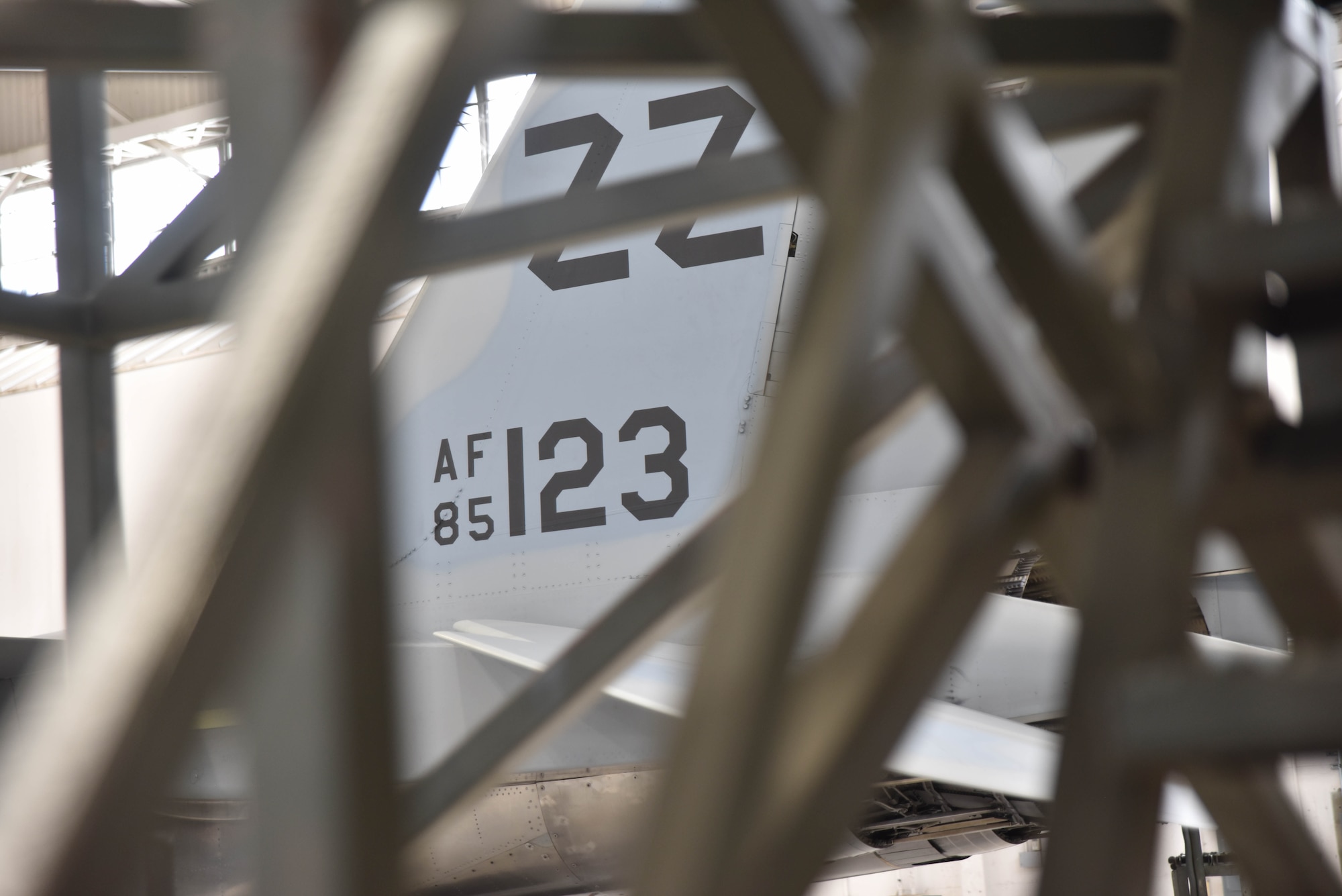 The tail number of a fighter jet is surrounded by metallic bars