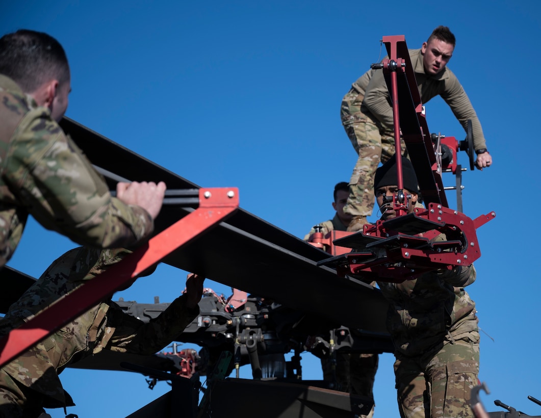 U.S. Army Soldiers from Task Force Rough Riders maneuver an AH-64E Apache helicopter blade into a folded position at Ali Al Salem Air Base, Kuwait, Jan. 11, 2023.