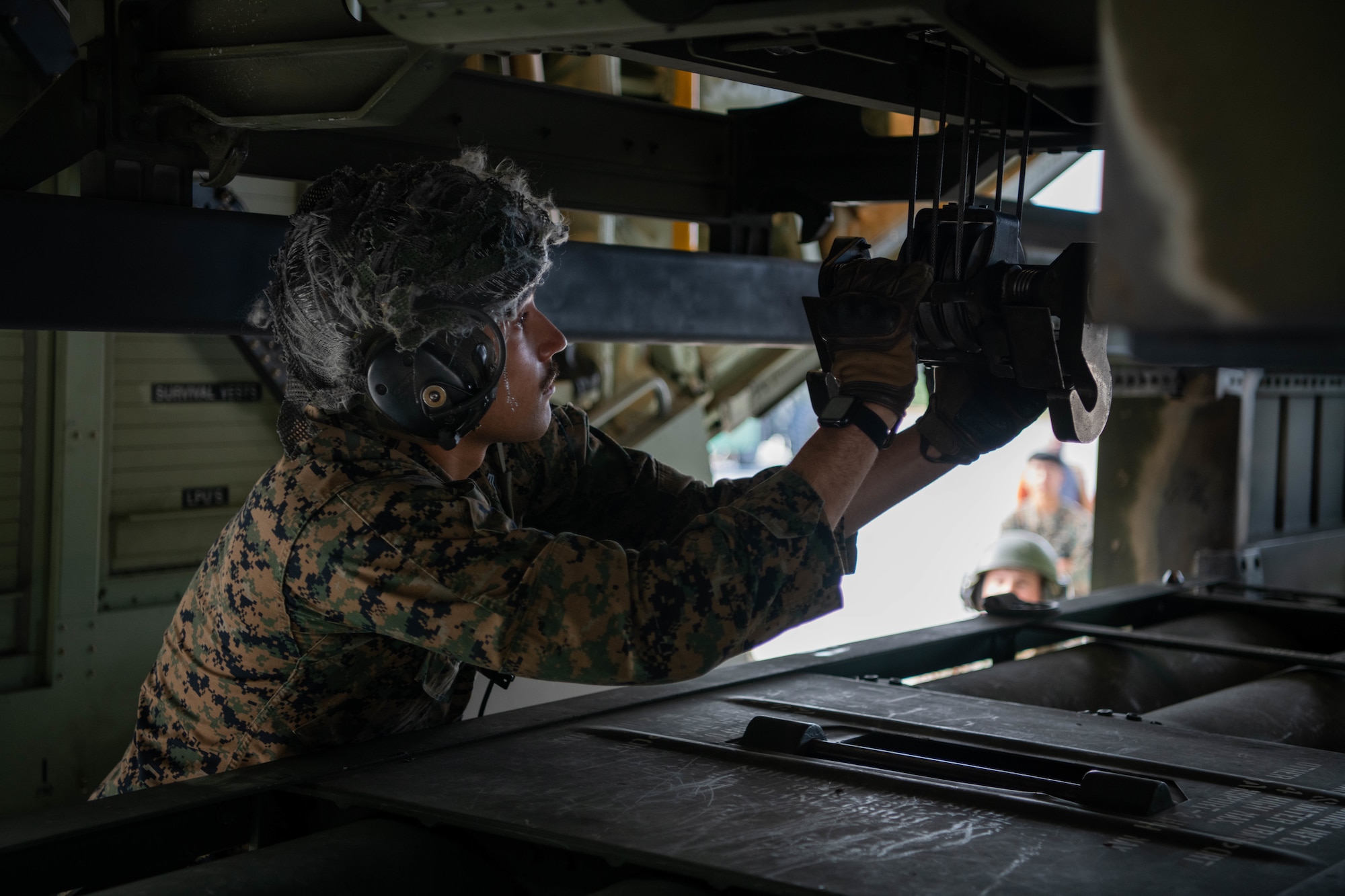 A Marine loads an ammo pod into an aircraft.