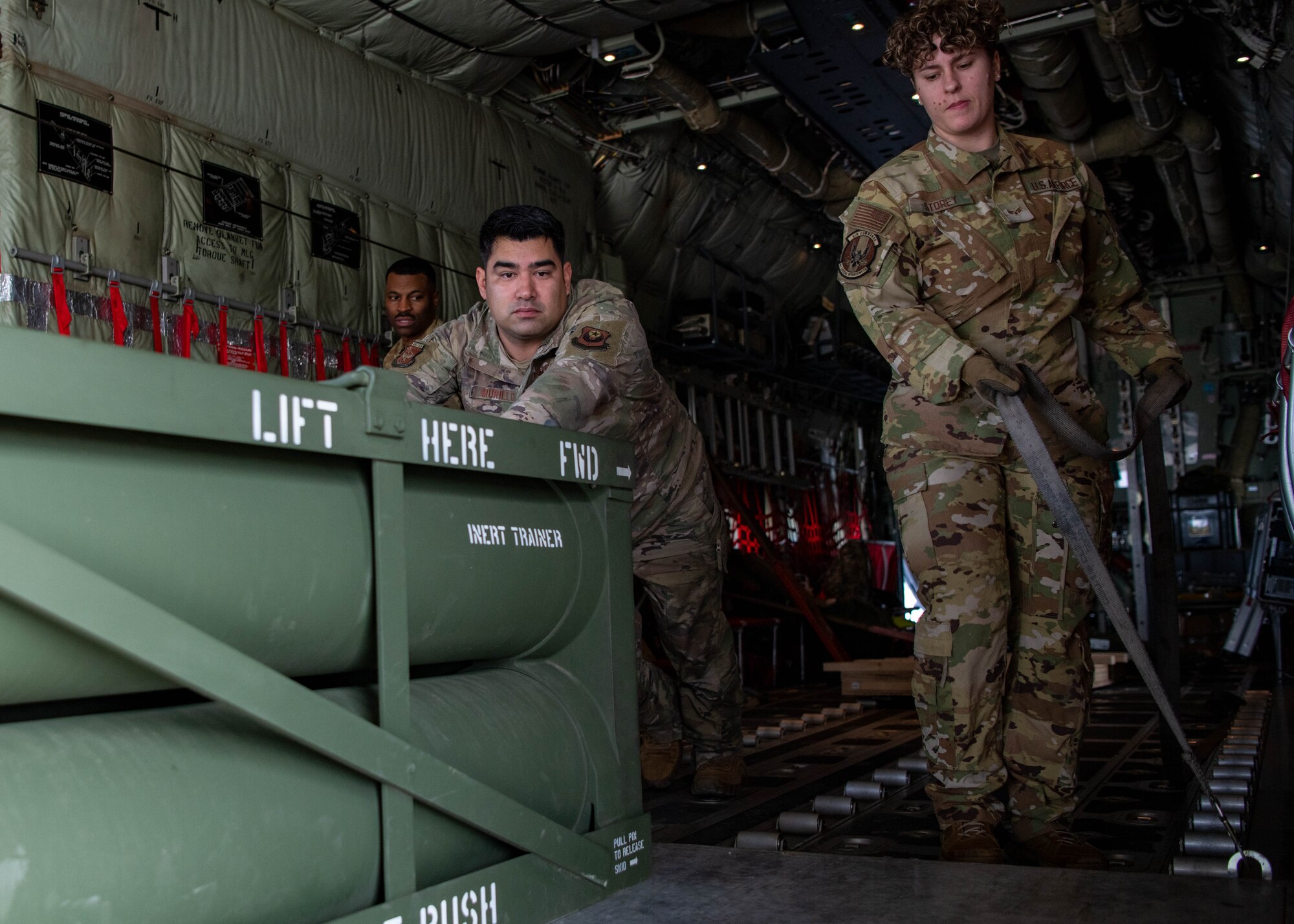 Airmen push an ammo pod in a cargo aircraft.