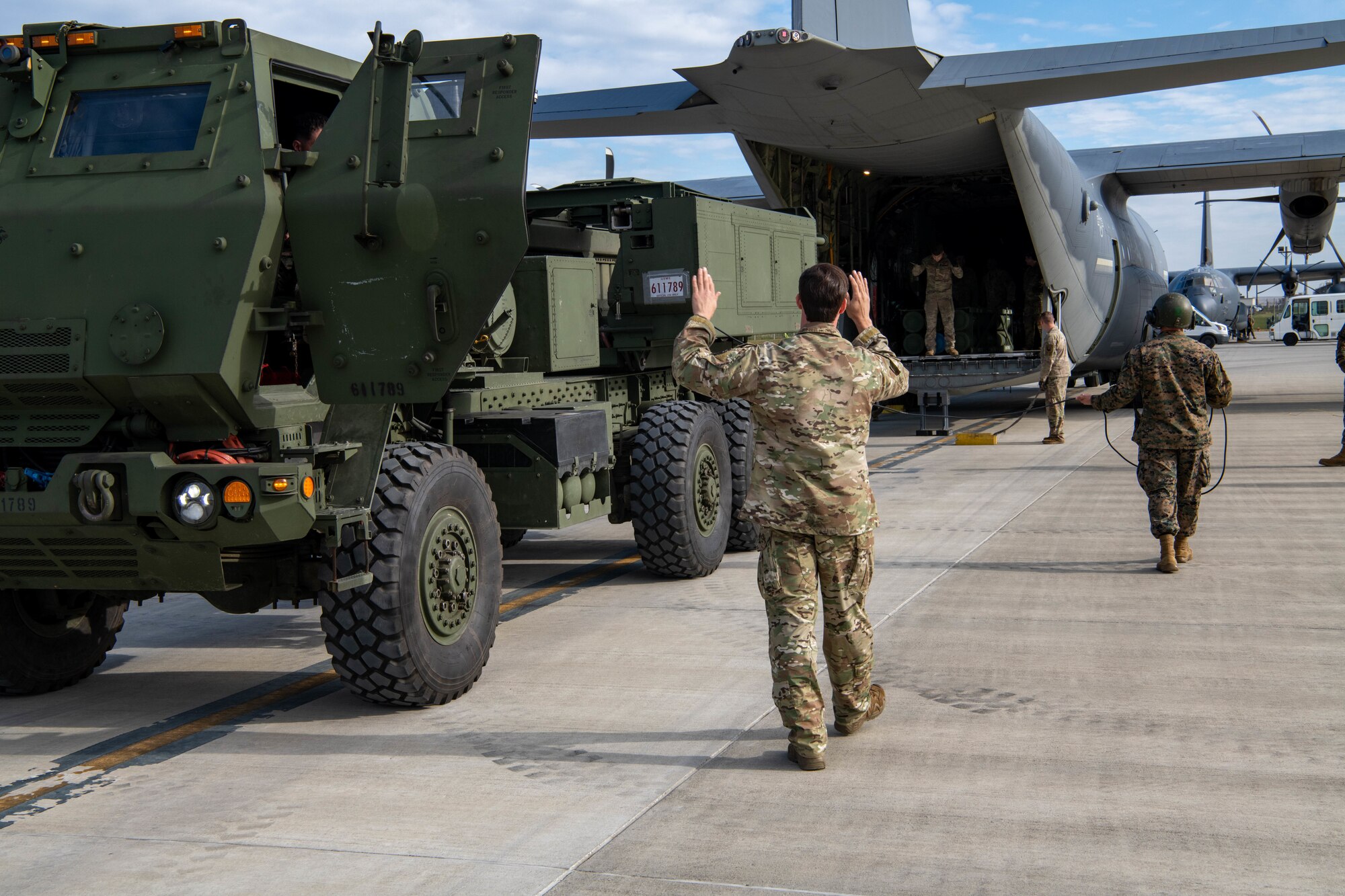 An Airmen marshals a vehicle.