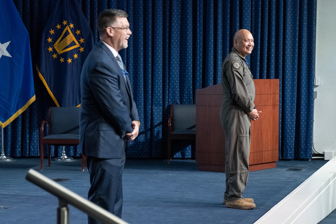 DLA Energy Commander Air Force Brig. Gen. Jimmy Canlas and Deputy Commander David Kless speak to an audience from a stage