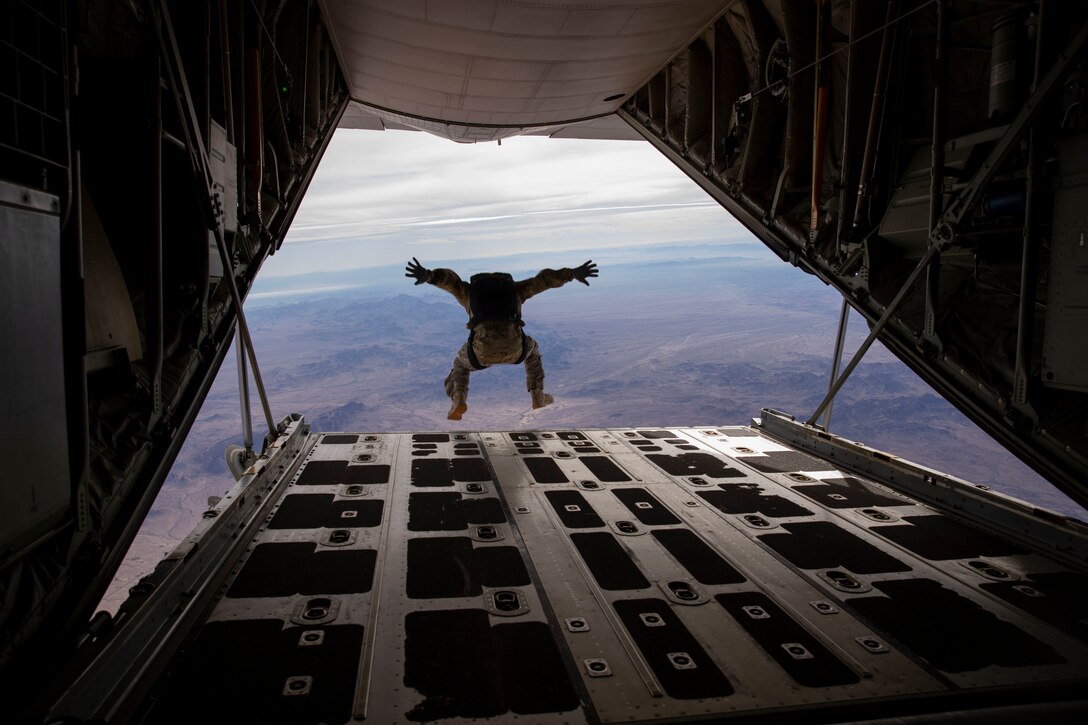 A paratrooper jumps out of the back of a plane.