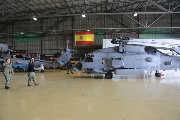 Sailors walk towards a helicopter.