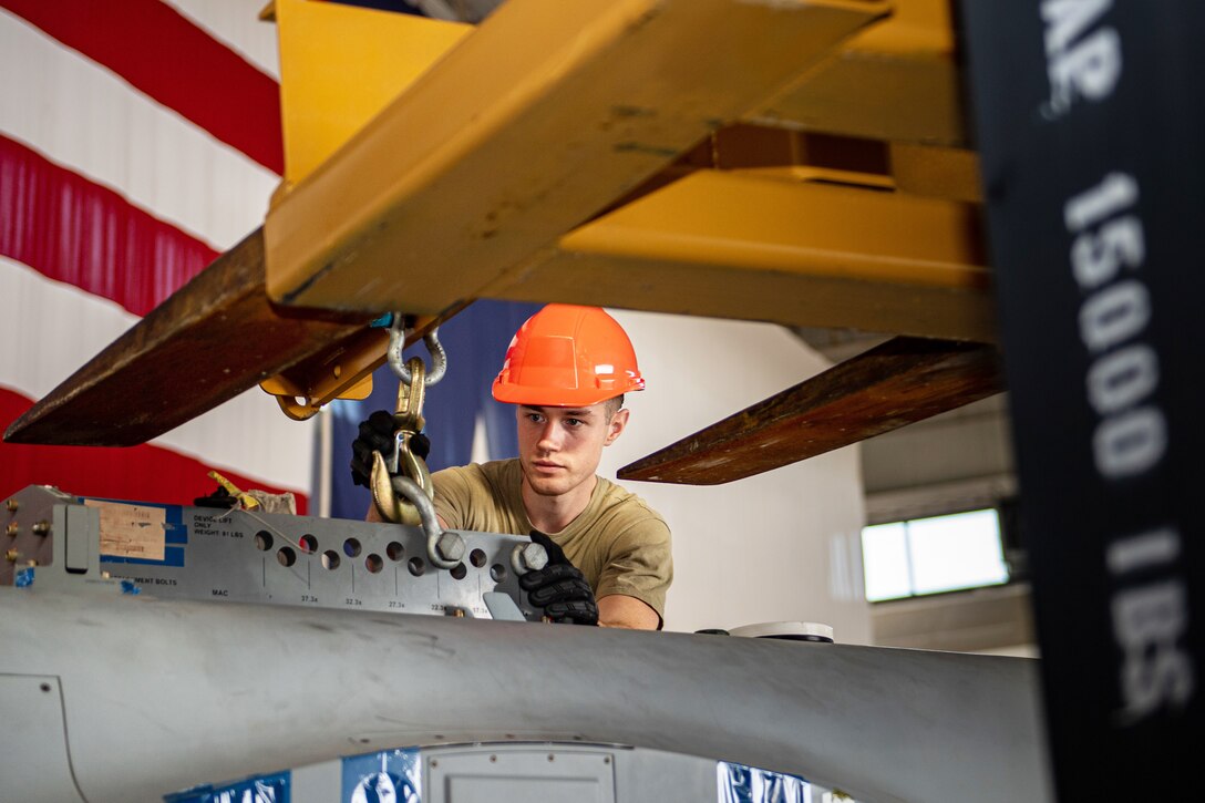 An airman wearing a hardhat assembles a small aircraft.