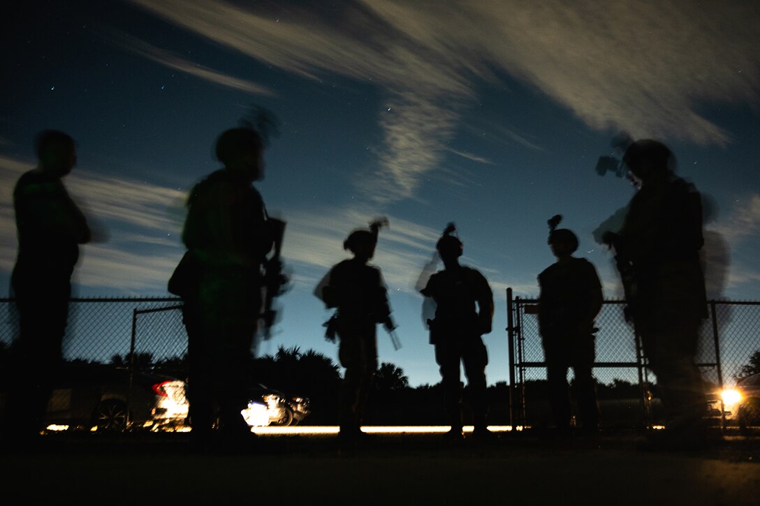 A team of airmen are shown standing outside in silhouette.