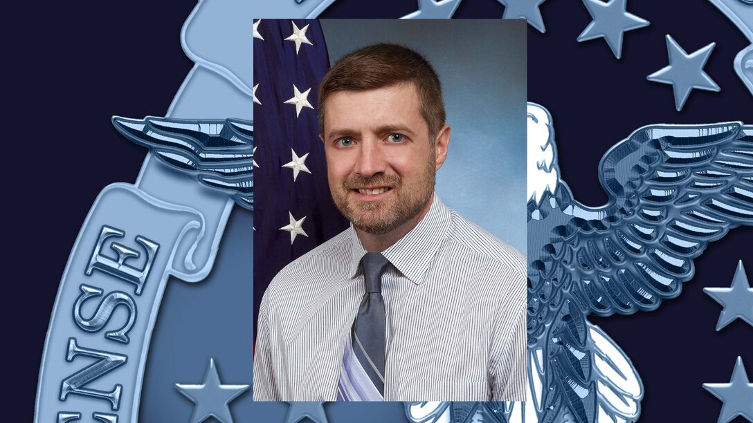 Official portrait of man with Defense Logistics Agency emblem in the background.
