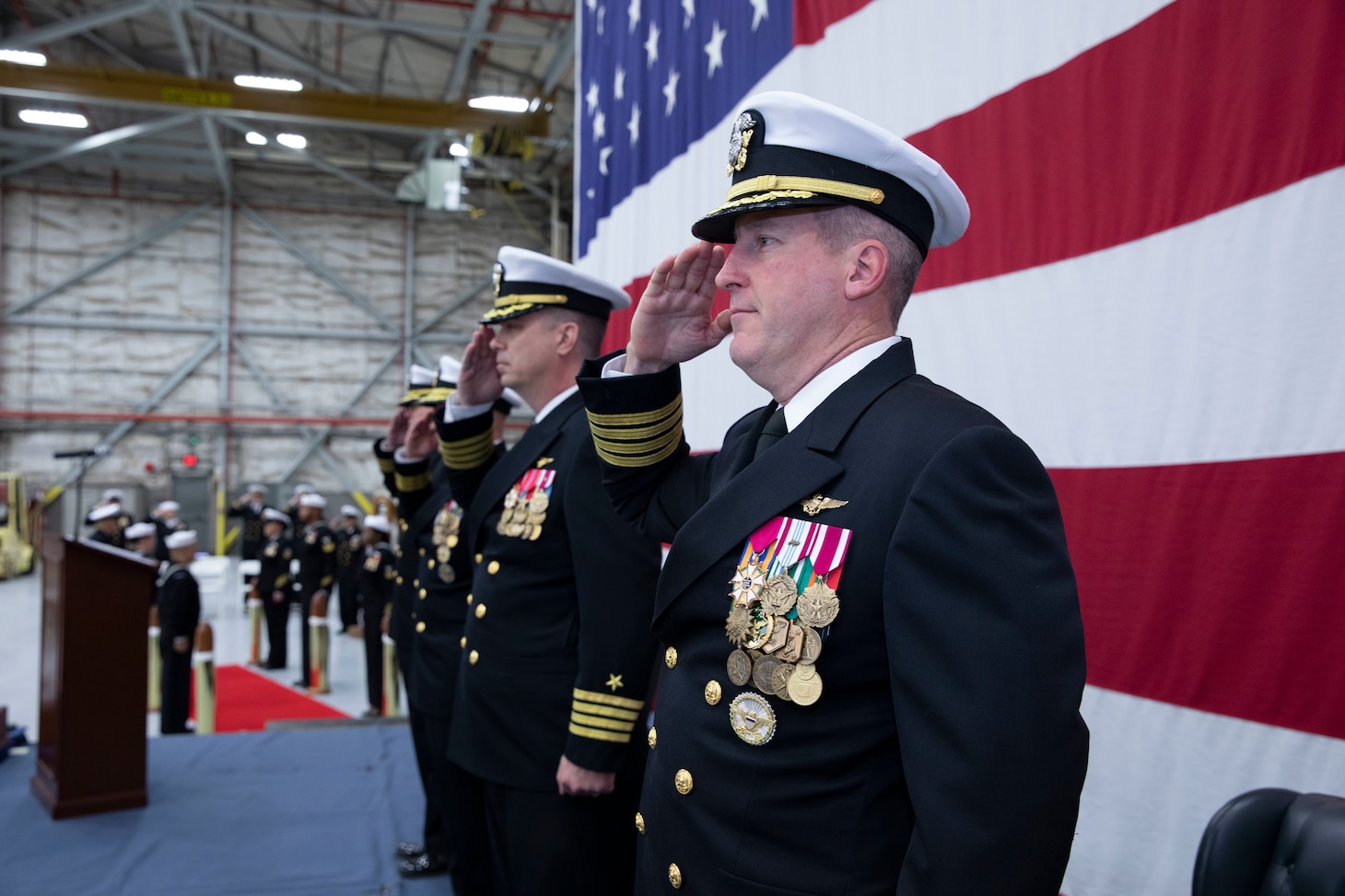 Capt. Dan Pugh (far right), incoming Commander, Fleet Logistics Support Wing (CFLSW), and Capt. Ian Hawley, outgoing CFLSW, salute during the presentation of the colors and national anthem at the CFLSW change of command ceremony.