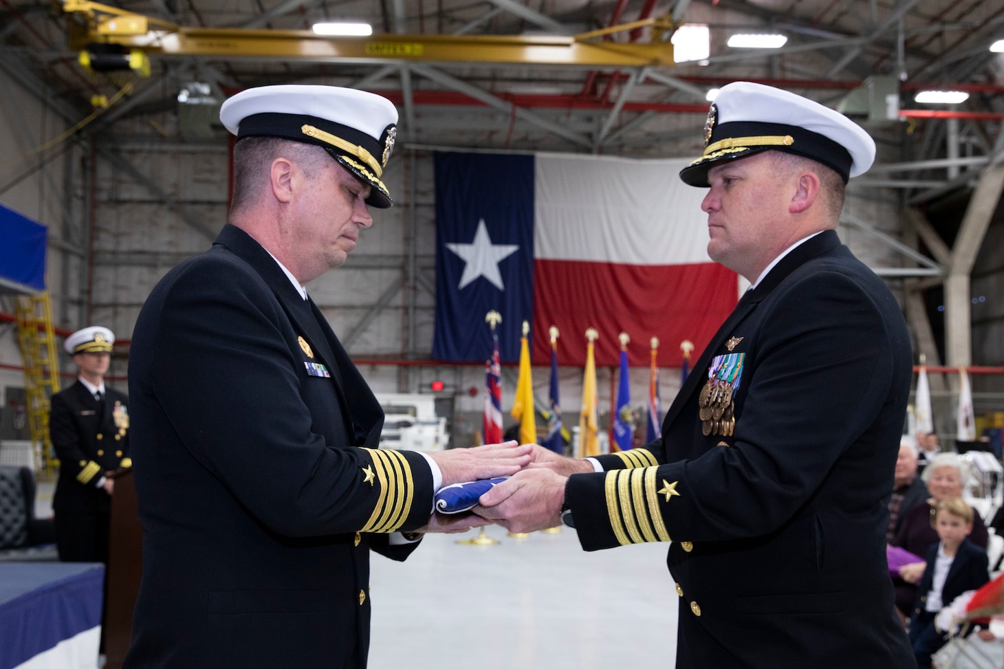 Capt. James Ward (right), Deputy Commodore of Commander, Fleet Logistics Support Wing (CFLSW), presents an American flag to outgoing CFLSW Capt. Ian Hawley (right) during Hawley's retirement ceremony.