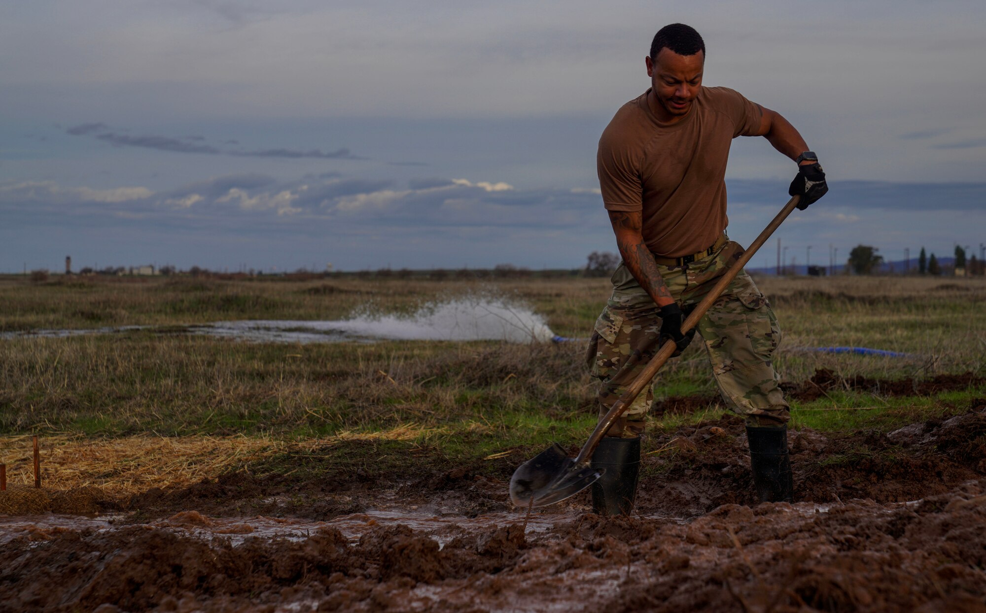 U.S. Air Force Staff Sgt. Terrell Phillips, 9th Civil Engineer Squadron pavement and heavy equipment supervisor, shovels dirt to clear a culvert Jan. 12, 2023, at Beale Air Force Base, Calif.