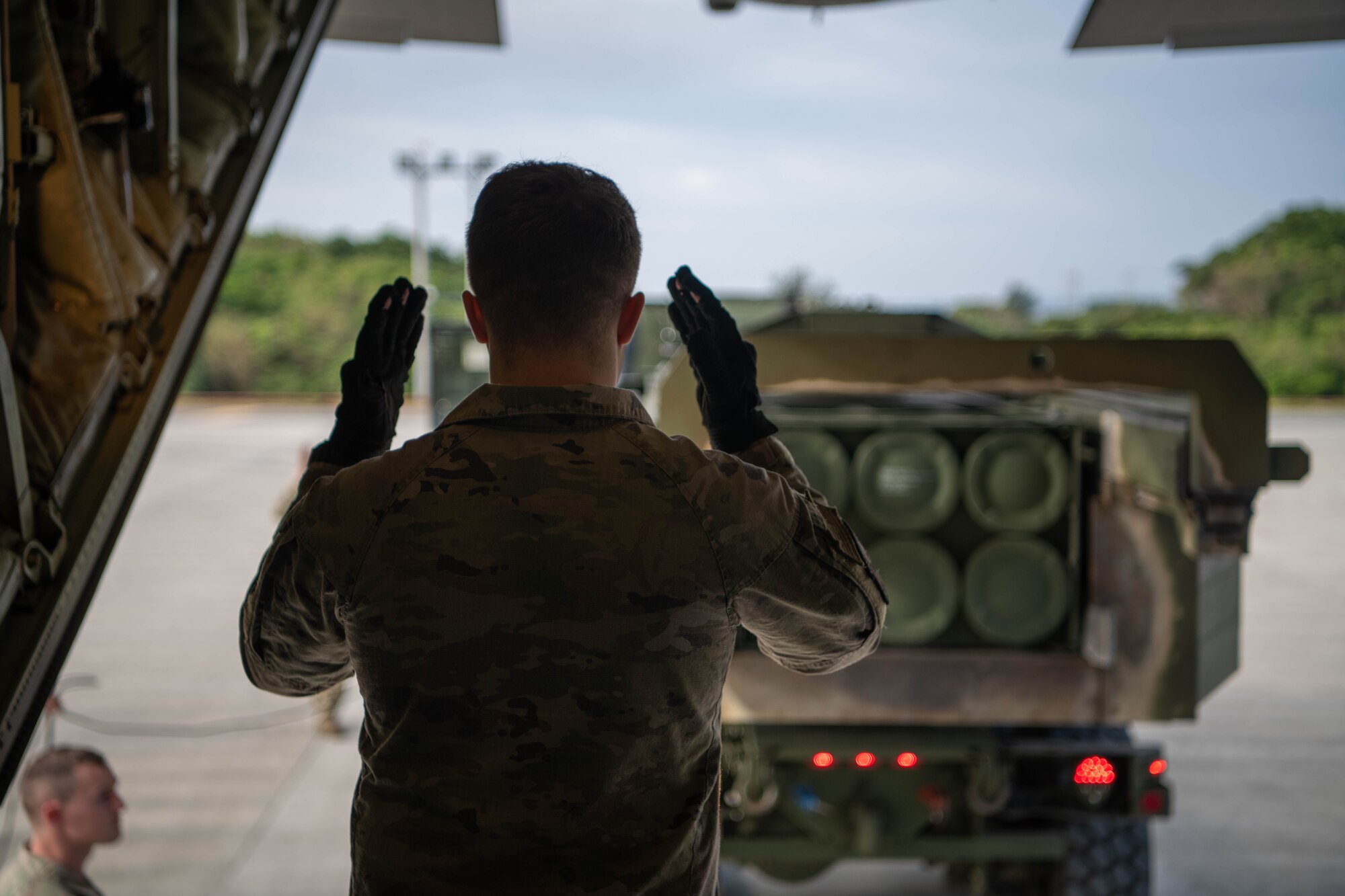 An Airman marshals a vehicle to a cargo aircraft.