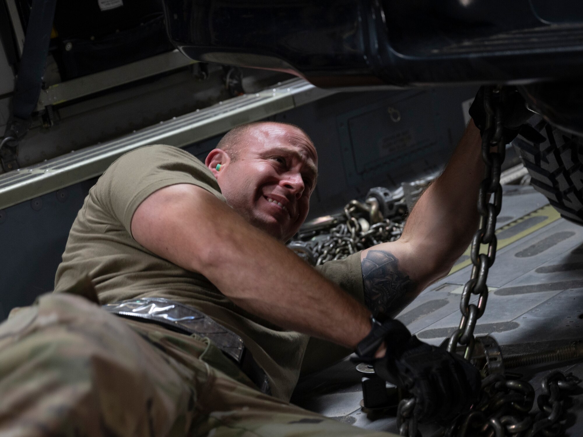 Air Force member chains down a compact pick-up truck to the floor of a C-17 Globemaster III.