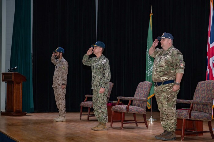 230118-N-EG592-1002 MANAMA, Bahrain (Jan. 18, 2023) From left to right, Royal Saudi Naval Forces Rear Adm. Abdullah Al-Mutairi; Vice Adm. Brad Cooper, commander of U.S. Naval Forces Central Command, U.S. 5th Fleet and Combined Maritime Forces; and United Kingdom’s Royal Navy Capt. James Byron stand for the national anthem during a change of command ceremony, Jan. 18, in Manama, Bahrain. Byron assumed command of Combined Task Force 150 which had been led by Al-Mutairi since July.