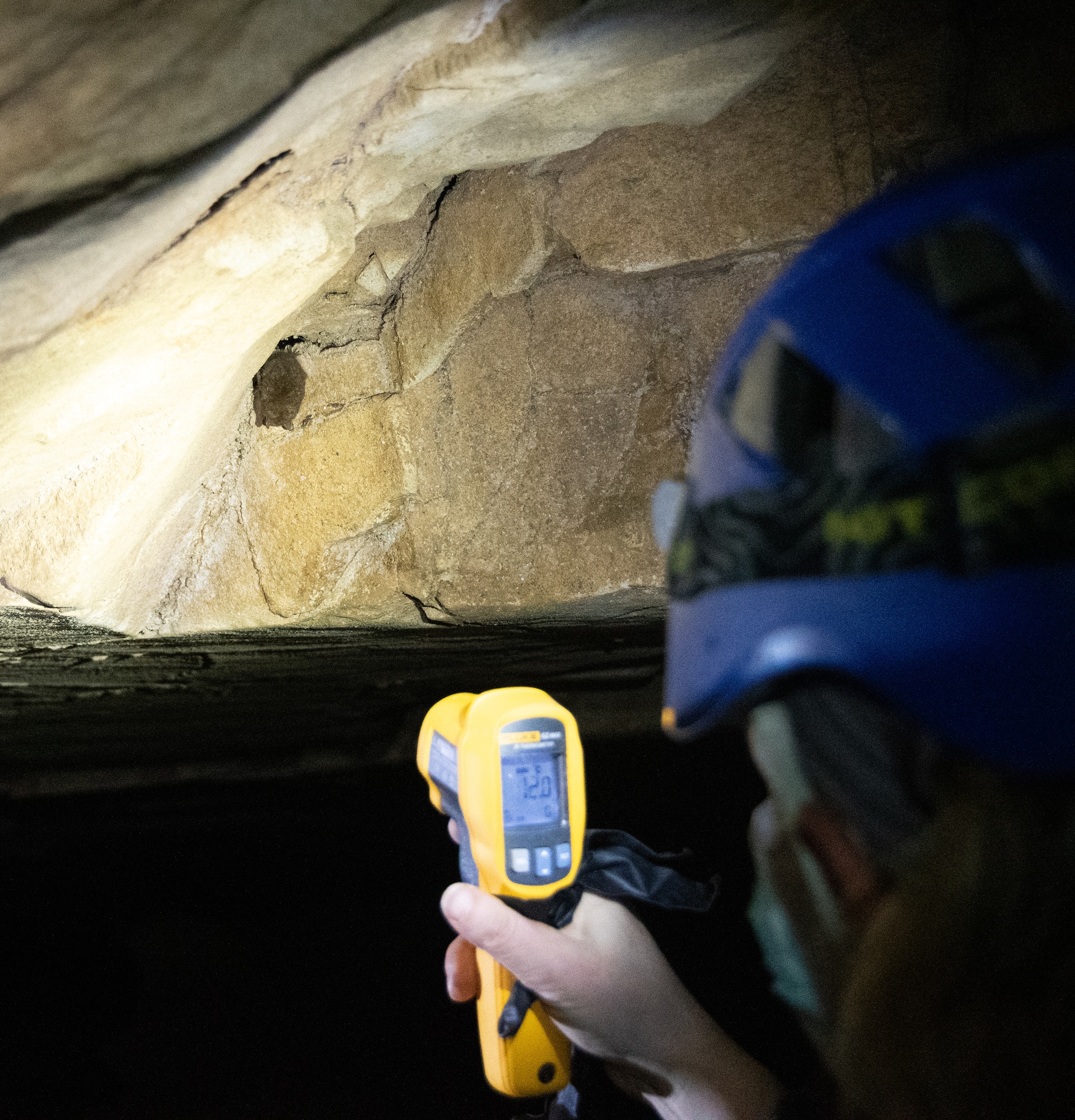 Biologist taking a surface temperature in a cave