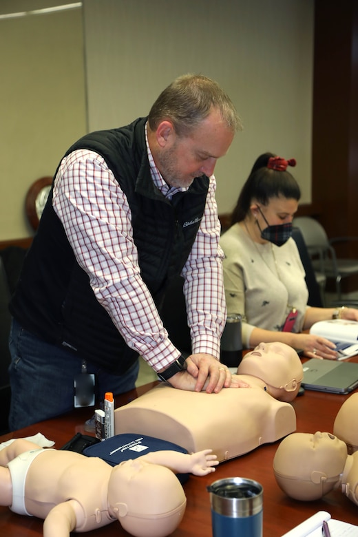 Man performs CPR on a CPR doll that is lying on a table.