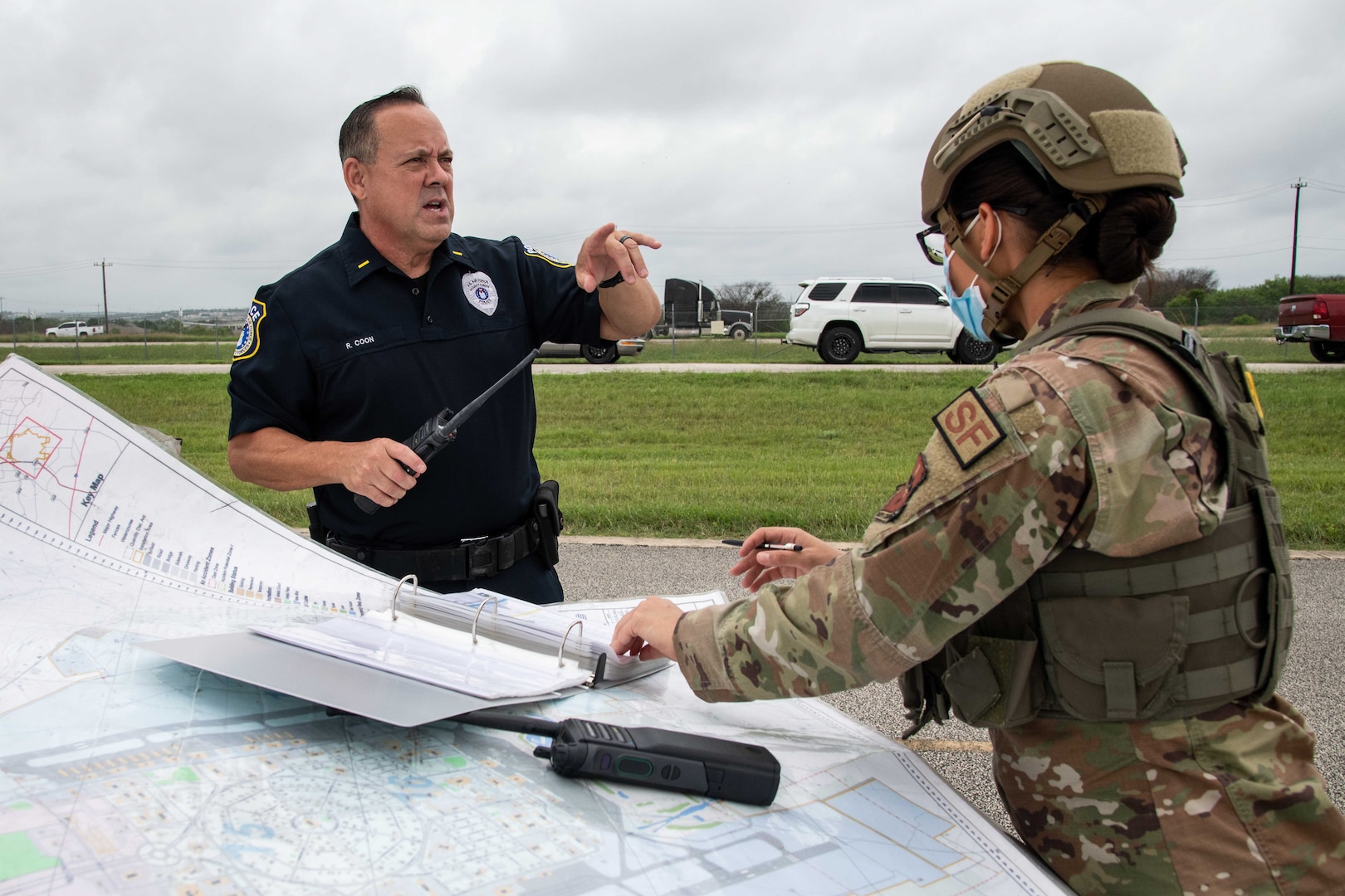 male civilian and female servicemember stand next hood of a vehicle