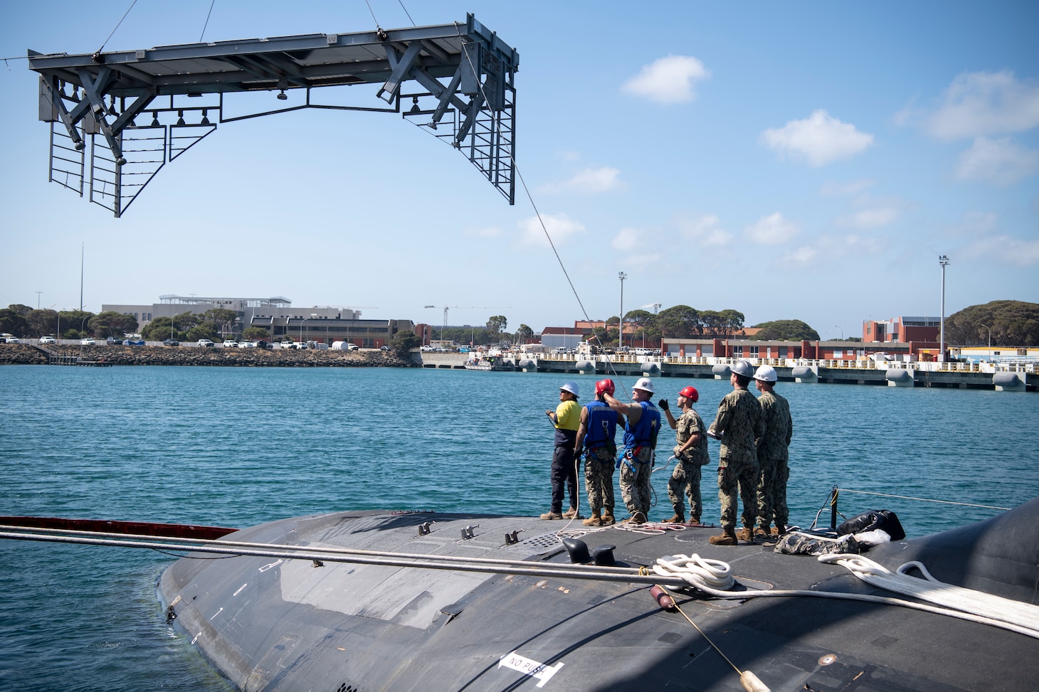 U.S. Navy Sailors assigned to the Virginia-class fast-attack submarine USS Mississippi (SSN 782) and explosive ordnance support personnel from Thales Australia lower the vertical launch system platform during a weapons-handling training exercise aboard the submarine while moored at HMAS Stirling Navy Base on Garden Island, Nov. 30. Mississippi conducted expeditionary reload training at HMAS Stirling, Australia, to enhance interoperability and communication, and strengthen relationships with the Royal Australian Navy.