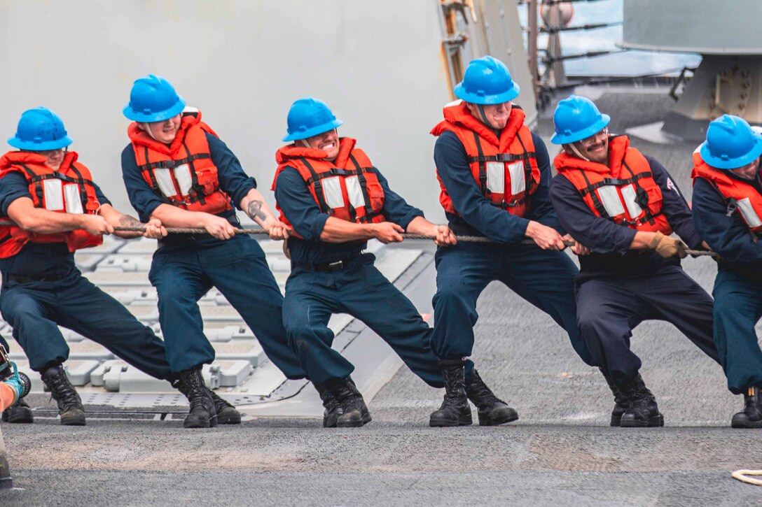 A group of sailors pull a rope.