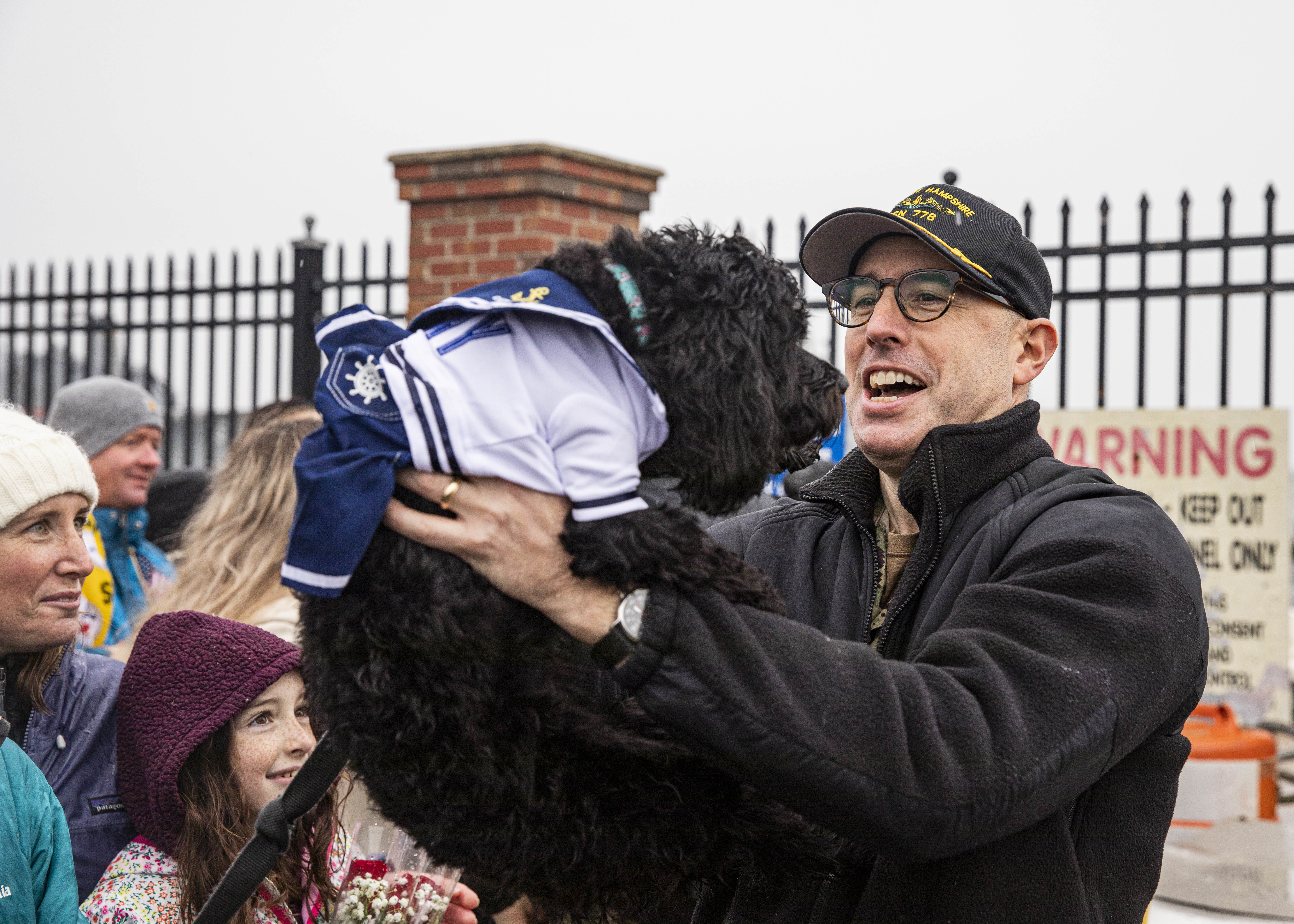 Capt. Bennett Christman, commanding officer of the Virginia-class fast-attack submarine USS New Hampshire (SSN 778), greets his dog during the boat's homecoming at Naval Station Norfolk, Jan. 17, 2023.