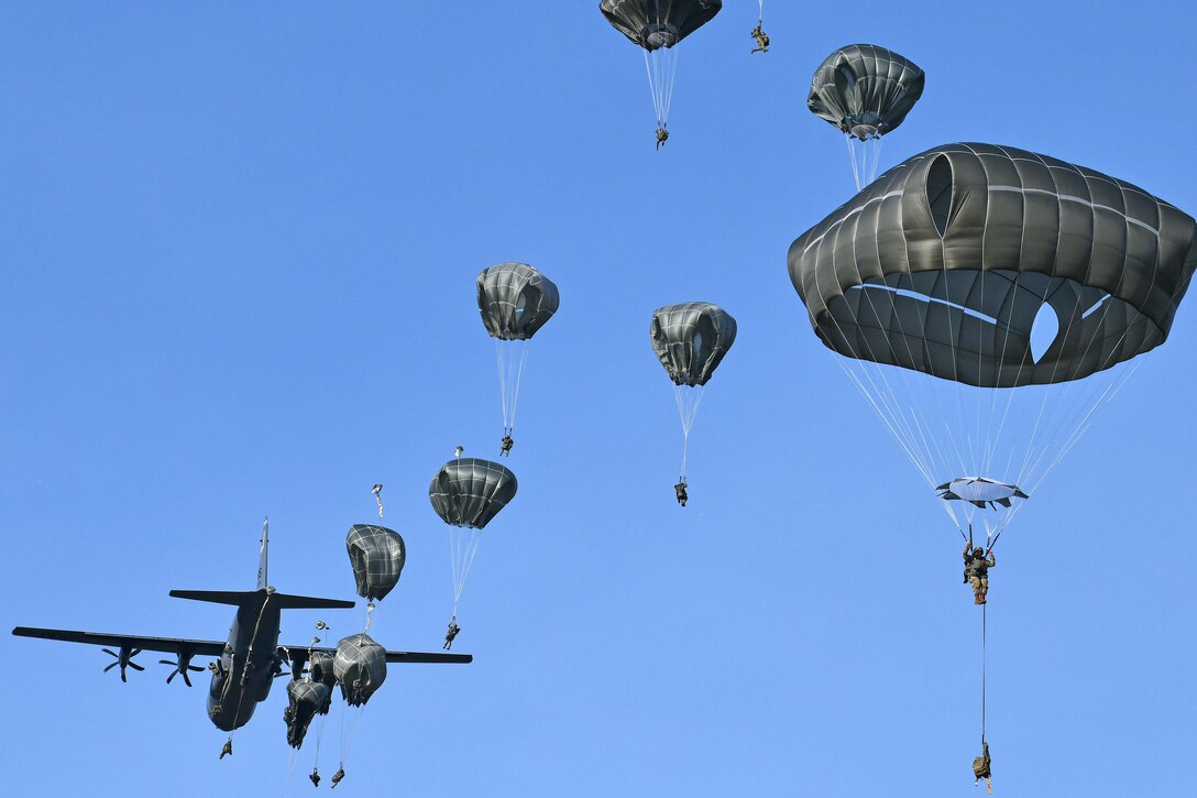 A group of paratroopers jump out of an aircraft.