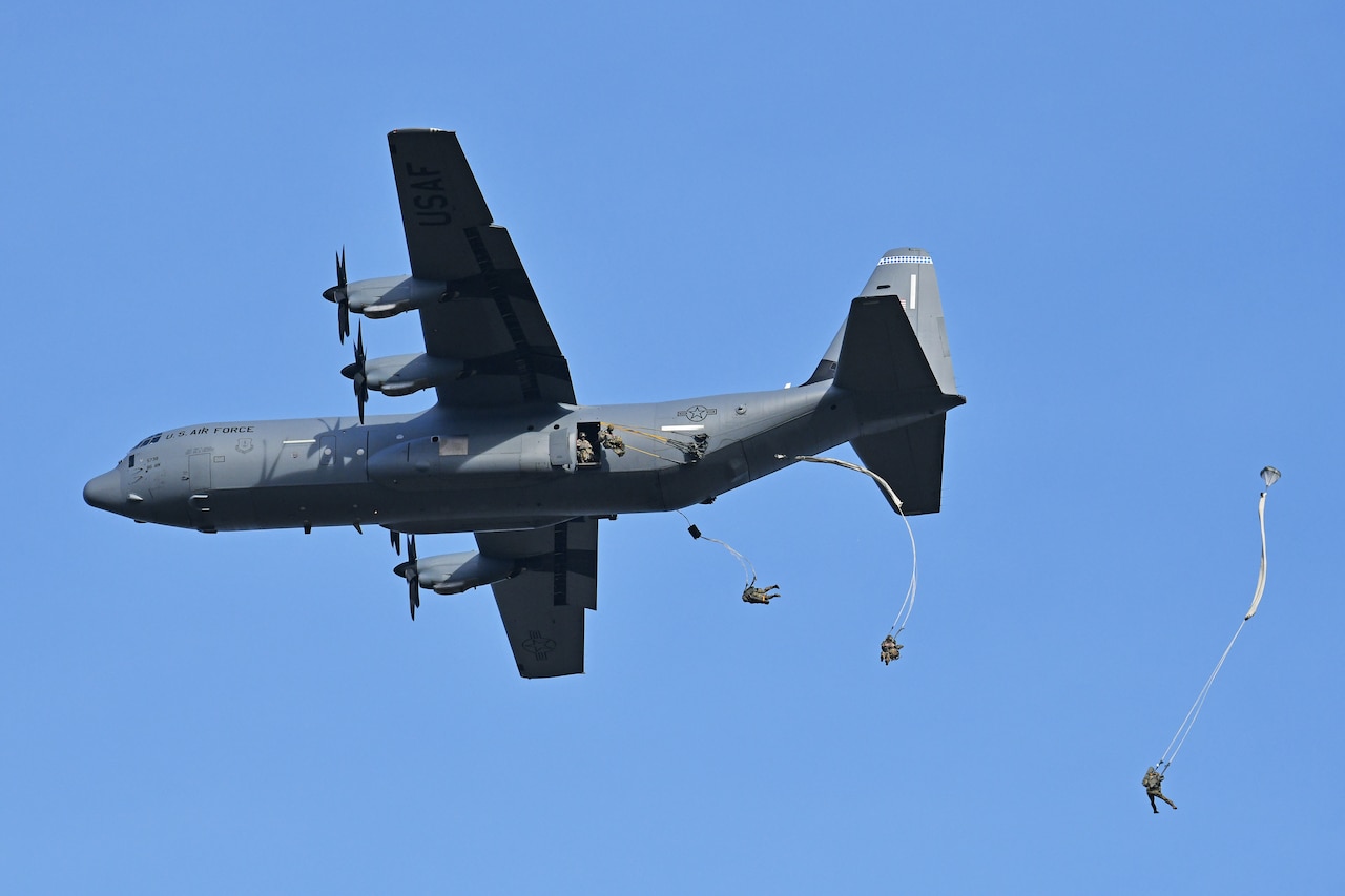 Paratroopers jump from an aircraft.