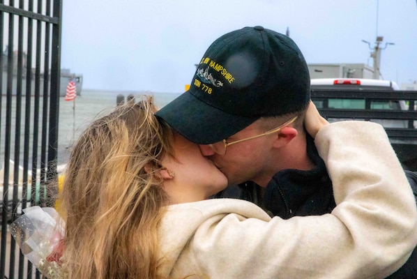 Seaman Fire Control Technician Tanner Hornsby, assigned to the Virginia-class fast-attack submarine USS New Hampshire (SSN 778), kisses his significant other as the traditional first kiss during the boat's homecoming at Naval Station Norfolk, Jan. 17, 2023.