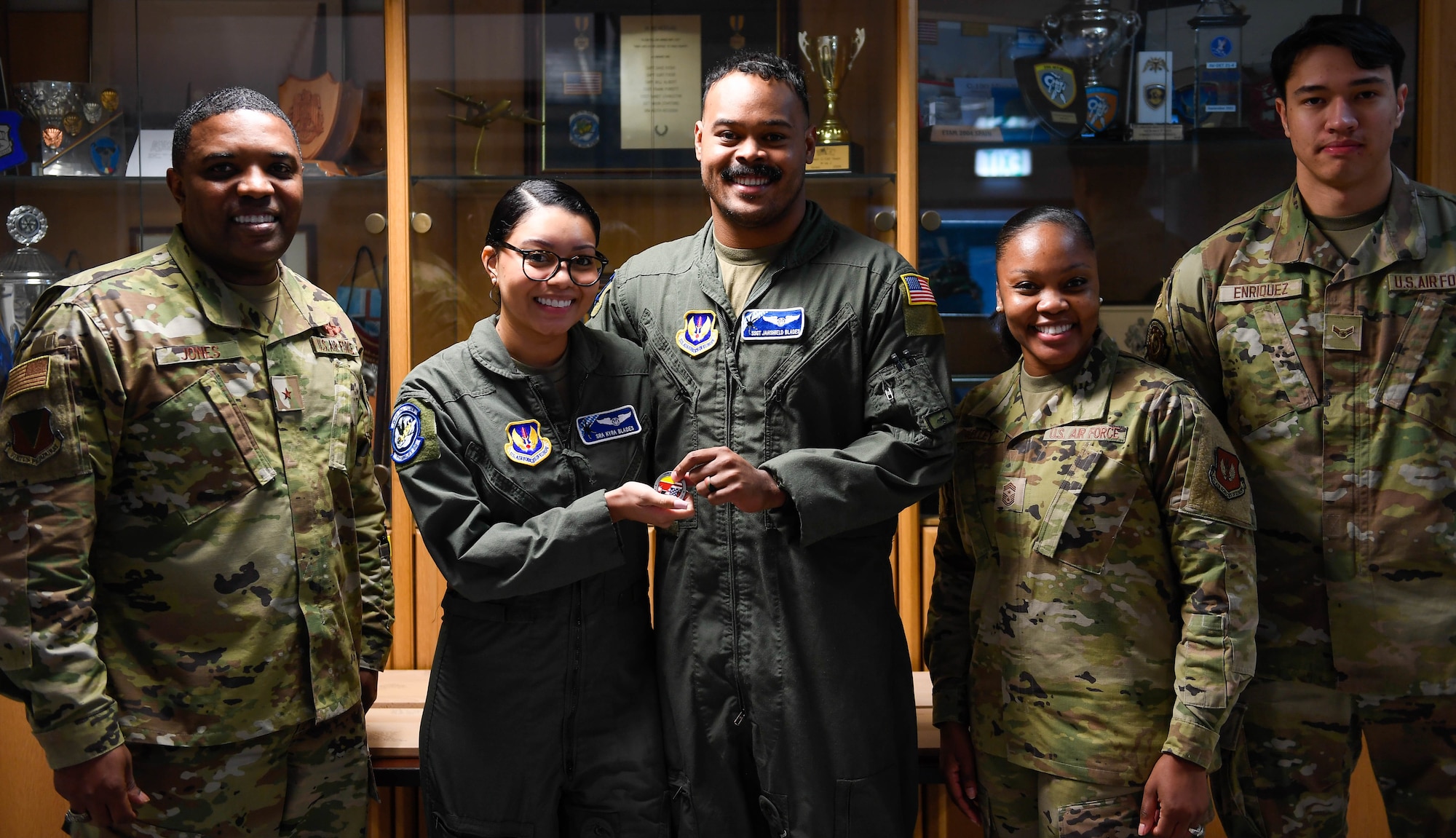 U.S. Air Force Staff Sgt. Jahshield Blades, 37th Airlift Squadron NCOIC of loadmaster development, center, presents his coin with his wife, Senior Airman Kyra Blades, at Ramstein Air Base, Germany, Jan. 12, 2023. They grew up together in Belize and his wife enlisted after seeing his positive experience in the U.S. Air Force as a loadmaster.