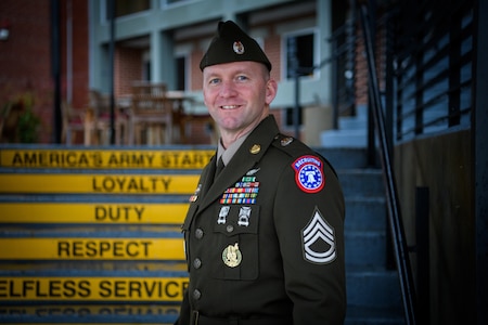 man wearing u.s. army uniform stands in front of staircase