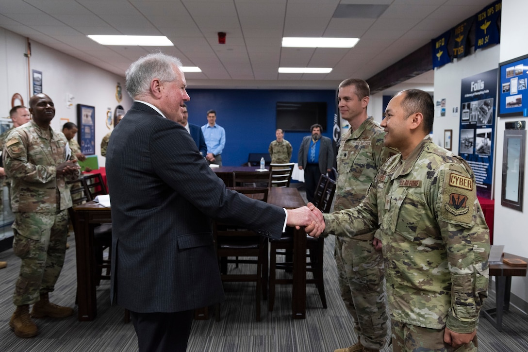 Staff Sgt. Noppharat Yaemsri (right), a cybersecurity specialist assigned to the 709th Cyberspace Squadron, Patrick Space Force Base, Fla., shakes the hand of Secretary of the Air Force Frank Kendall after the service’s top civilian presented his coin to the Airman.  Kendall came to the Air Force Technical Applications Center Jan. 18, 2023 to learn more about how the nuclear treaty monitoring center performs its global nuclear deterrence mission.  “AFTAC is a unique organization filled with skilled technical experts, and I am inspired to see the level of commitment they have,” Kendall said. Also pictured are Col. James A. Finlayson, (far left), AFTAC commander, and Lt. Col. Aaron Lake (second from right), 709th CYS commander.  (U.S. Air Force photo by Matthew S. Jurgens)