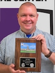 Scott Legge shows the plaque he received for earning Walter Reed National Military Medical Center's 2022 Senior Civilian of the Year, Administrative, awarded to him in January.