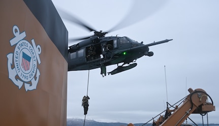 Coast Guard Maritime Security Response Team West members fast-rope from a 210th Rescue Squadron Alaska Air National Guard HH-60G Pave Hawk combat search and rescue  helicopter onto the Coast Guard Cutter Cypress in Kodiak, Alaska, Jan. 11, 2023, during a joint service training exercise. The MSRT West members maintain a ready alert force to support Coast Guard operational commanders and Department of Defense combatant commanders.