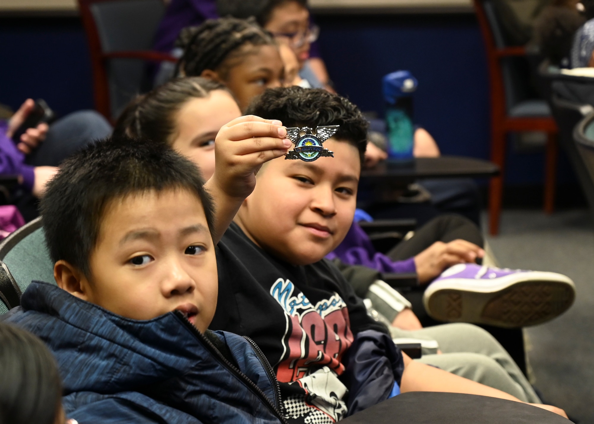 A student from Stafford Elementary School, Tacoma, receives a coin from U.S. Air Force Col. David Fazenbaker, 62d Airlift Wing commander, during an Aviation Inspiration and Mentorship (AIM) event at Joint Base Lewis-McChord, Washington, Jan. 17, 2023. AIM is a community outreach program that is designed to inform, influence and inspire the next generation of Air Force aviators. (U.S. Air Force photo by Senior Airman Callie Norton)