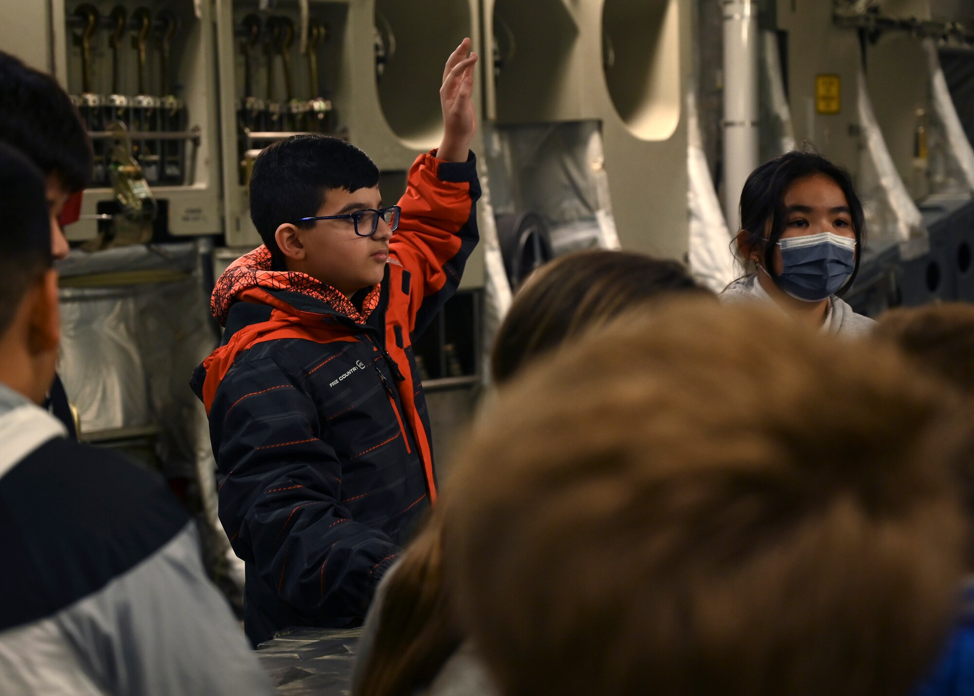 A student from Stafford Elementary School, Tacoma, raises his hand to ask a question while touring a C-17 Globemaster III assigned to the 62d Airlift Wing, during an Aviation Inspiration and Mentorship (AIM) event at Joint Base Lewis-McChord, Washington, Jan. 17, 2023. AIM is a community outreach program that is designed to inform, influence and inspire the next generation of Air Force aviators. (U.S. Air Force photo by Senior Airman Callie Norton)