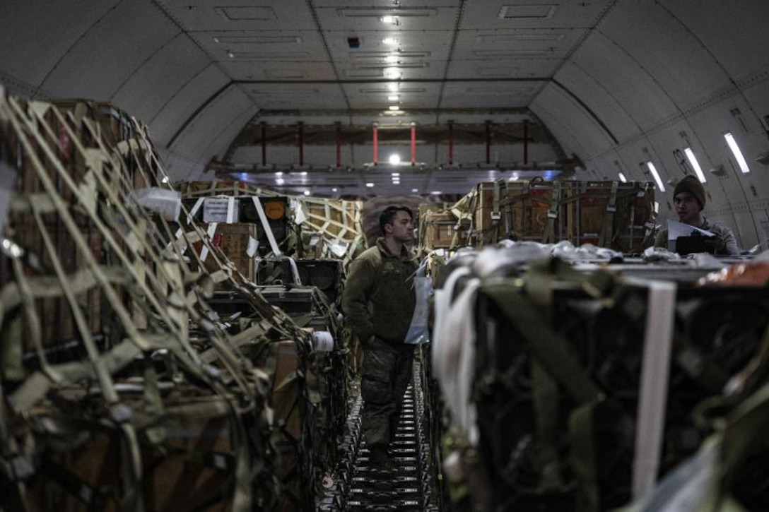 Two men check cargo on an airplane.