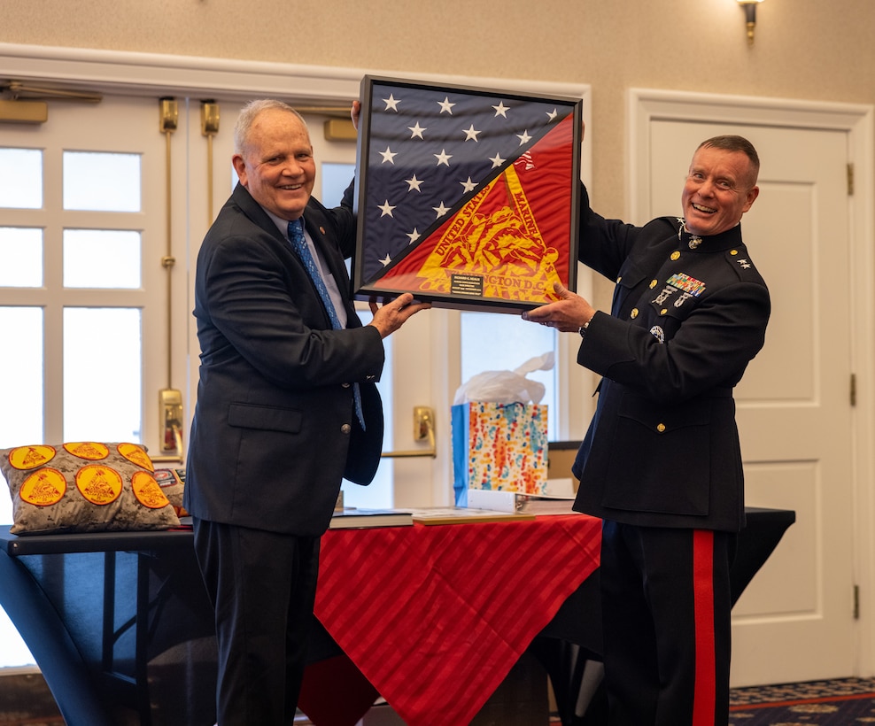Rick Nealis, director of the Marine Corps Marathon Organization, left, is handed a gift by U.S. Marine Corps Major Gen. David Maxwell, commander of Marine Corps Installations Command, right, during Nealis’ retirement ceremony at The Clubs at Quantico, Virginia, Jan. 18, 2023. Rick Nealis served as the director of the Marine Corps Marathon Organization for 30 years and served as an active duty Marine for 20 years.  (U.S. Marine Corps by Lance Cpl. Jeffery Stevens)