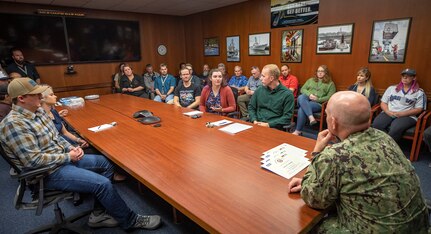 Capt. Jip Mosman, commander, Puget Sound Naval Shipyard & Intermediate Maintenance Facility (right) listens to feedback from a group of recent graduates of the Lean Six Sigma Black Belt course Sept. 19, 2022, at PSNS & IMF in Bremerton, Wash. (U.S. Navy photo by Scott Hansen)