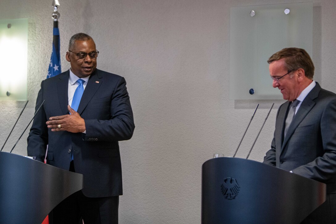 Secretary of Defense Lloyd J. Austin III and his German counterpart speak from behind lecterns.