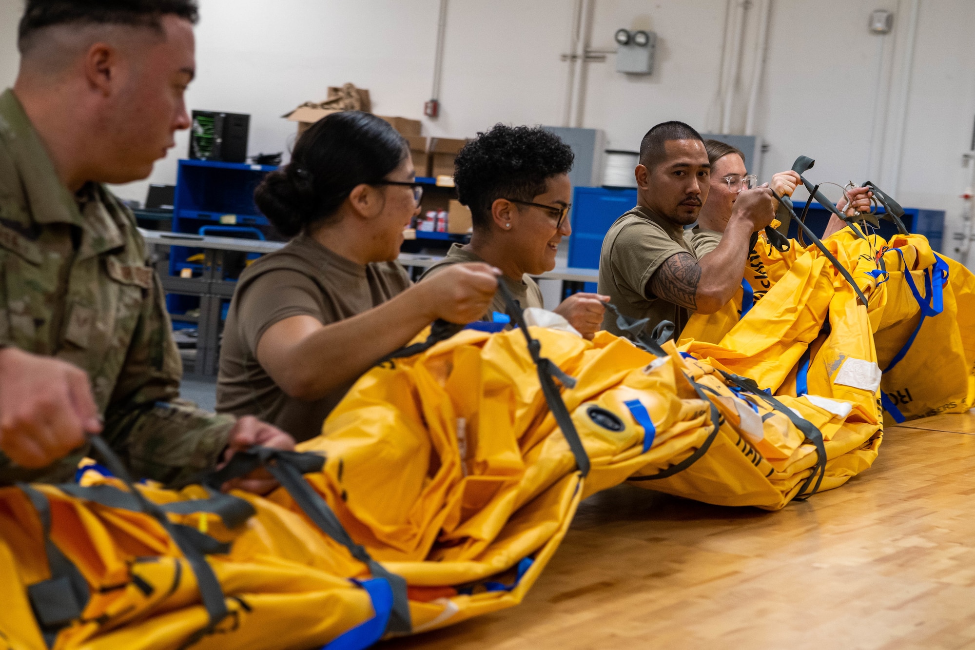 Airmen from 15th Operations Support Squadron aircrew flight equipment shop pack a 46-man life raft after performing survival equipment functional checks at Joint Base Pearl Harbor-Hickam, Hawaii, Jan. 11, 2023. AFE specialists ensure aircrew have the necessary supplies for in-flight emergency use, providing safety to the crew and passengers. (U.S. Air Force photo by Senior Airman Makensie Cooper)