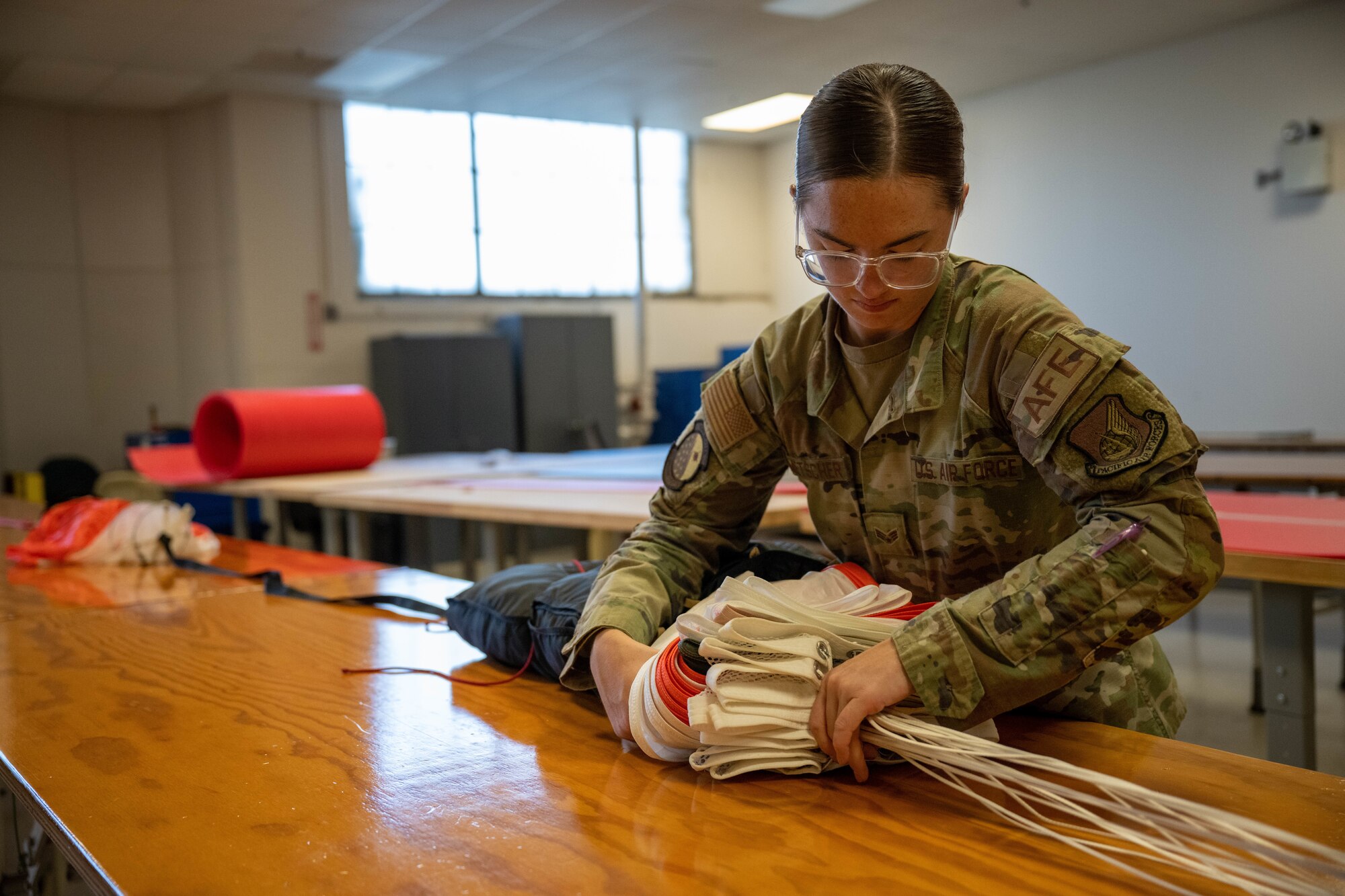 Senior Airman Karlie Kometscher, 15th Operations Support Squadron aircrew flight equipment journeyman, works on a Butler Parachute BA-30 low profile parachute system at Joint Base Pearl Harbor-Hickam, Hawaii, Jan. 11, 2023. AFE technicians are responsible for all emergency floatation devices and parachutes on Hickam aircraft. (U.S. Air Force photo by Senior Airman Makensie Cooper)