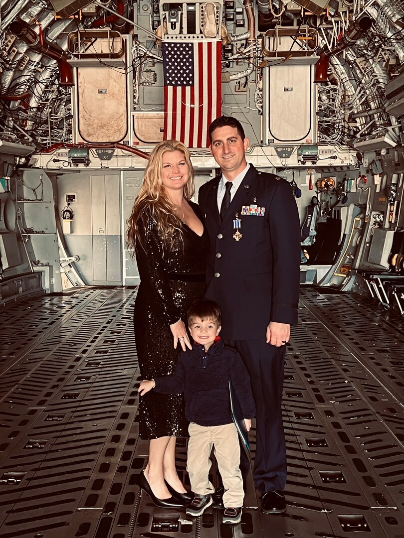 U.S. Air Force Maj. (Dr.) Dominick Vitale, Brooke Army Medical Center critical care/trauma surgeon, stands inside a C-17 Globemaster III with wife Megan O’Toole and son Antonio Vitale after receiving the Distinguished Flying Cross at Travis Air Force Base, Calif., Dec. 9, 2022. Vitale and members of a Critical Care Air Transport Team were on the first aircraft to land and evacuate the severely injured following the Aug. 26, 2021 suicide bombing near Hamid Karzai International Airport, Kabul, Afghanistan. (DoD courtesy photo)
