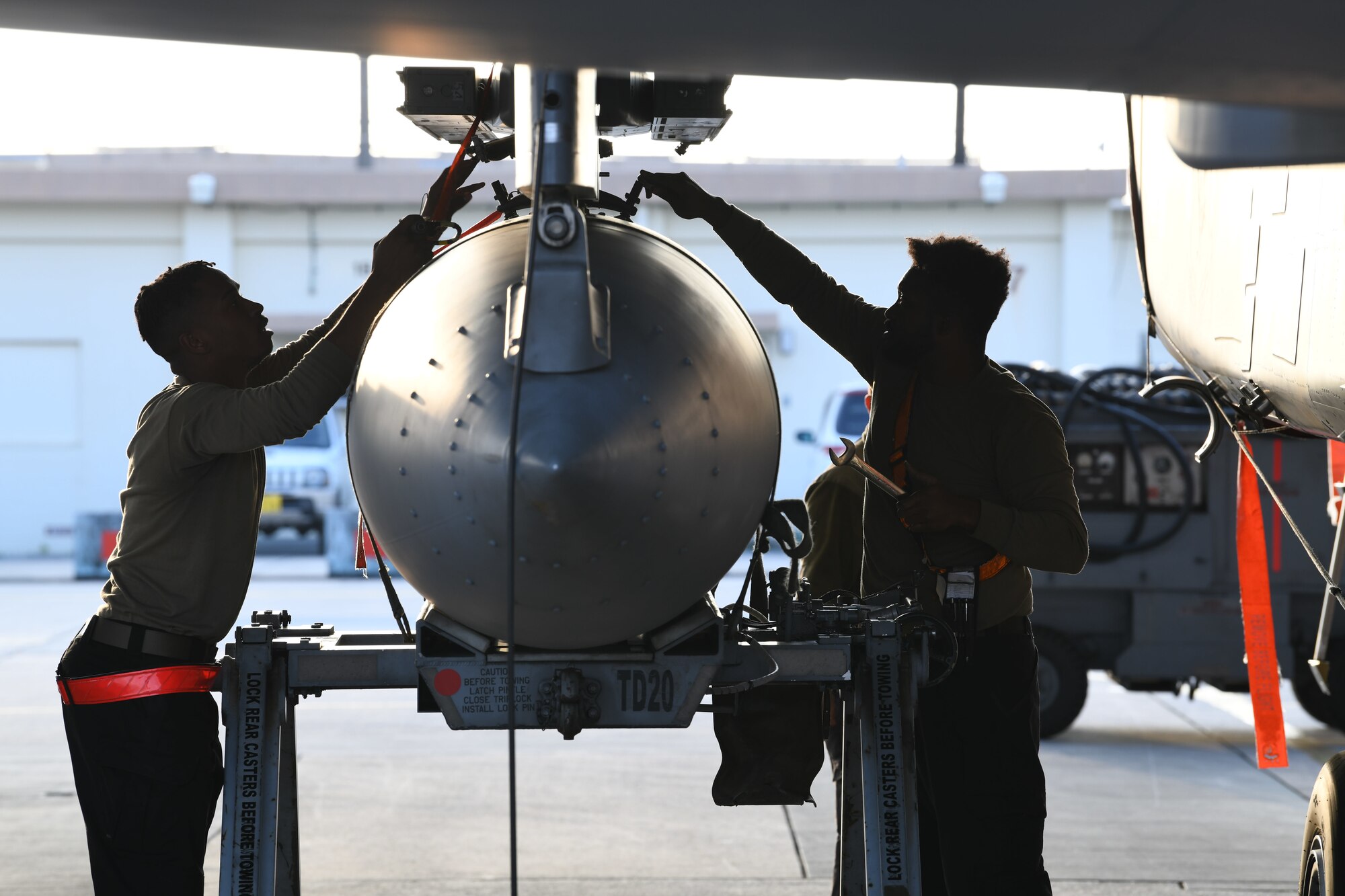 Airmen remove a fuel tank from a fighter jet.