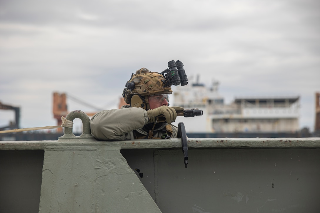 A U.S. Marine with the Maritime Special Purpose Force (MSPF), 26th Marine Expeditionary Unit (MEU), peeks over the side of a cargo ship during a Visit, Board, Search, and Seizure (VBSS) course at Fort Eustis, Virginia, Jan. 12, 2023. Marines with the MSPF and BLT 1/6 conducted boat assault force operations to further advance their qualifications to conduct VBSS operations during their upcoming deployment with the 26th MEU. The VBSS course is designed by Expeditionary Operations Training Group to train MSPF, BLT 1/6, and supporting enablers across the Marine Air Ground Task Force to conduct Maritime Interception Operations in preparation for the Amphibious Ready Group/Marine Expeditionary Unit (ARG/MEU) deployment.