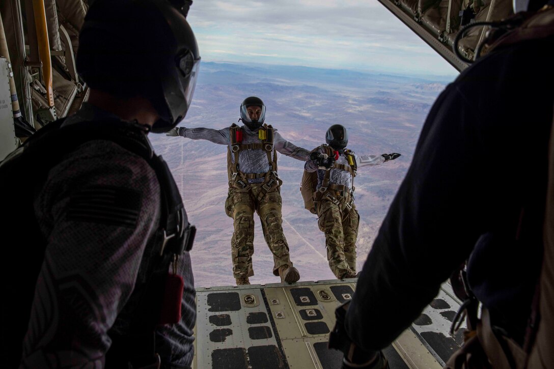 Two soldiers fall backwards out of an airborne aircraft.